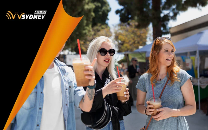 Visitors enjoying food and wine tastings at St Ives Village Green under market umbrellas with festival banners in the background, Sydney event