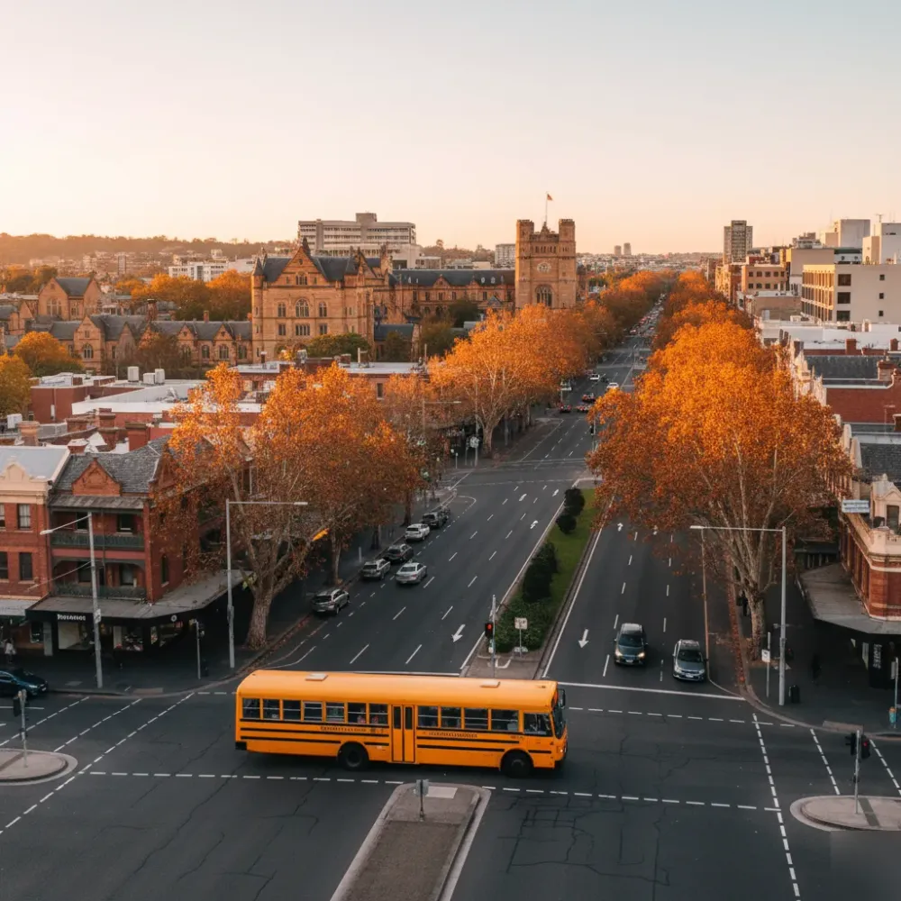 School bus service travelling through inner Sydney near heritage university buildings at golden hour